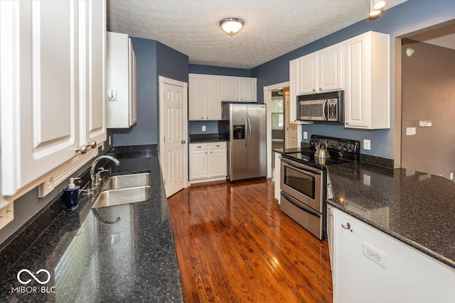 2325 N Talbott St, Indianapolis, IN 46205 - kitchen with stainless steel appliances, white cabinetry, dark wood-style floors, a textured ceiling, and dark stone counters