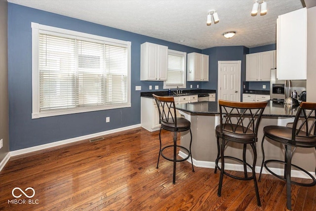 2325 N Talbott St, Indianapolis, IN 46205 - kitchen featuring stainless steel appliances, dark countertops, a peninsula, white cabinets, and a breakfast bar