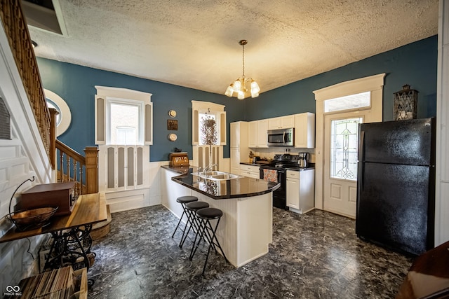 426 N Franklin St, Greensburg, IN 47240 - kitchen featuring black appliances, dark countertops, a textured ceiling, a kitchen breakfast bar, and a peninsula
