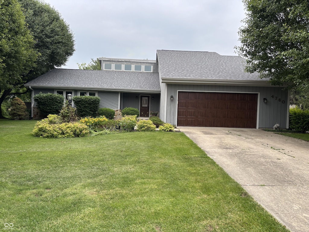4760 Winterberry Pl, Columbus, IN 47201 - mid-century home featuring an attached garage, concrete driveway, a front yard, and a shingled roof