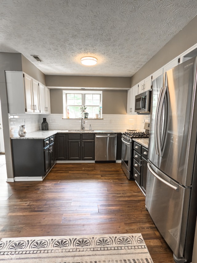7470 Charrington Ct, Indianapolis, IN 46254 - kitchen featuring stainless steel appliances, white cabinets, dark wood finished floors, backsplash, and a textured ceiling