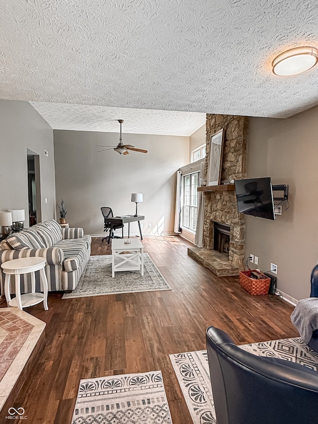 7470 Charrington Ct, Indianapolis, IN 46254 - living room featuring a textured ceiling, a ceiling fan, dark wood-style floors, and a stone fireplace