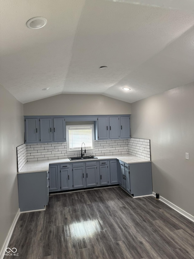 1006 Hurricane St, Franklin, IN 46131 - kitchen featuring dark wood finished floors, vaulted ceiling, backsplash, light countertops, and blue cabinets