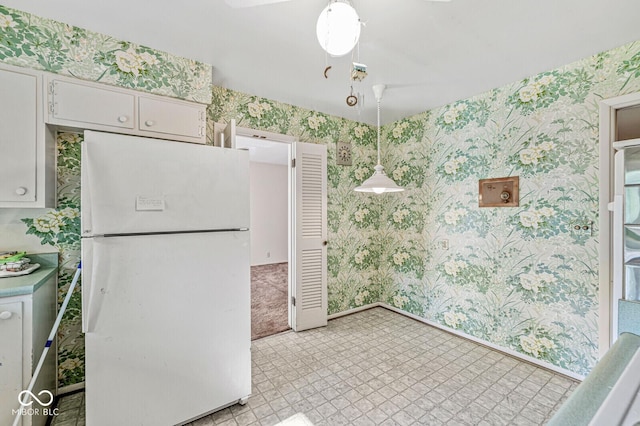 5841 N Parker Ave, Indianapolis, IN 46220 - kitchen with freestanding refrigerator, wallpapered walls, light flooring, white cabinets, and hanging light fixtures