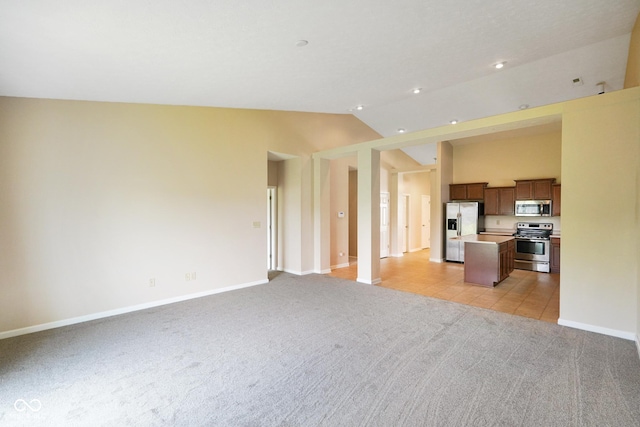 7715 Bolero Dr, Camby, IN 46113 - unfurnished living room with light colored carpet, lofted ceiling, recessed lighting, and light tile patterned flooring