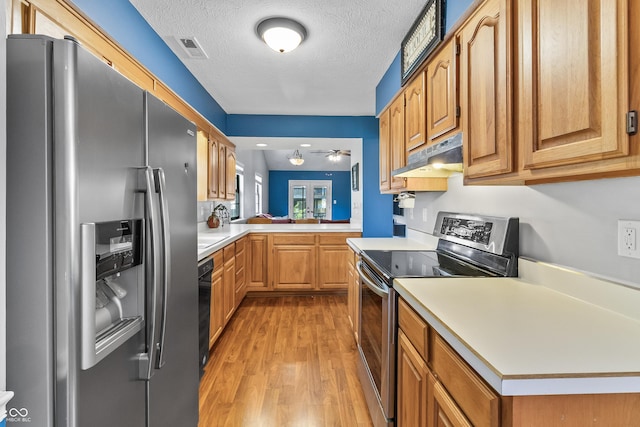 7616 Derrek Pl, Indianapolis, IN 46219 - kitchen featuring appliances with stainless steel finishes, under cabinet range hood, light countertops, light wood finished floors, and a textured ceiling