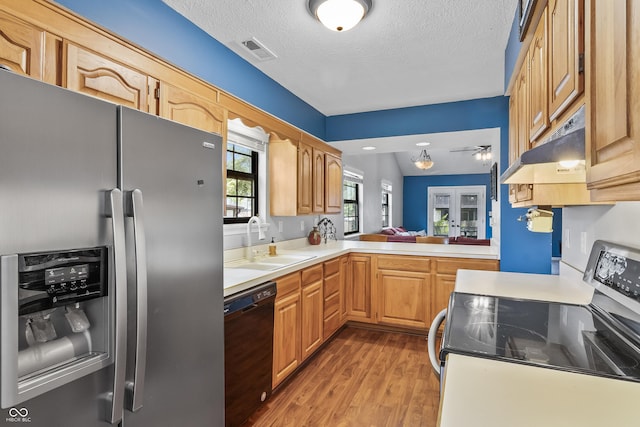 7616 Derrek Pl, Indianapolis, IN 46219 - kitchen with stainless steel appliances, under cabinet range hood, wood finished floors, a textured ceiling, and light countertops