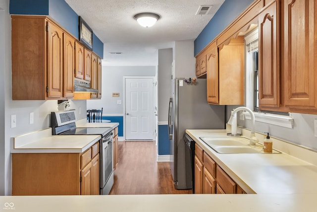 7616 Derrek Pl, Indianapolis, IN 46219 - kitchen with stainless steel electric range oven, under cabinet range hood, dark wood-style flooring, light countertops, and a textured ceiling