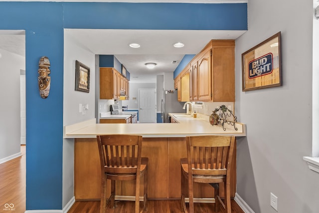 7616 Derrek Pl, Indianapolis, IN 46219 - kitchen featuring stove, dark wood finished floors, light countertops, a kitchen breakfast bar, and recessed lighting