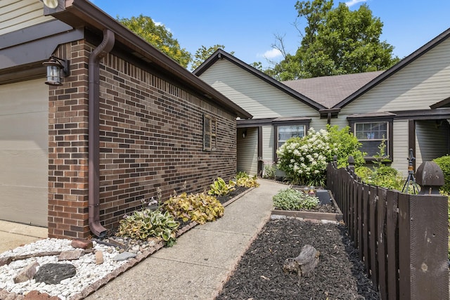 7616 Derrek Pl, Indianapolis, IN 46219 - view of side of home with an attached garage, a vegetable garden, and brick siding