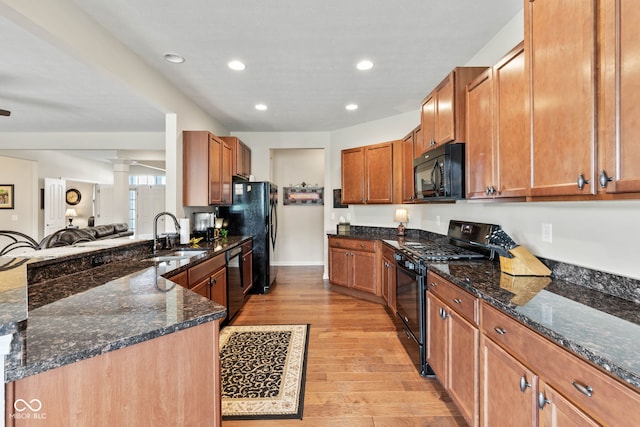 13327 Hockley Dr, Fishers, IN 46037 - kitchen featuring black appliances, light wood-type flooring, dark stone countertops, a peninsula, and ornate columns