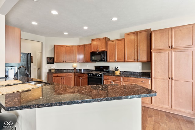 13327 Hockley Dr, Fishers, IN 46037 - kitchen with black appliances, light wood-type flooring, dark stone counters, recessed lighting, and a breakfast bar