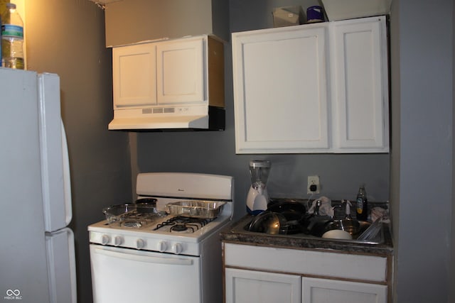 1703 E 34th St, Indianapolis, IN 46218 - kitchen with white appliances, under cabinet range hood, dark countertops, and white cabinets
