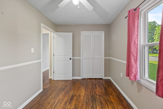 900 N College St N, Veedersburg, IN 47987 - unfurnished bedroom with dark wood-style flooring, multiple windows, a closet, a textured ceiling, and a ceiling fan