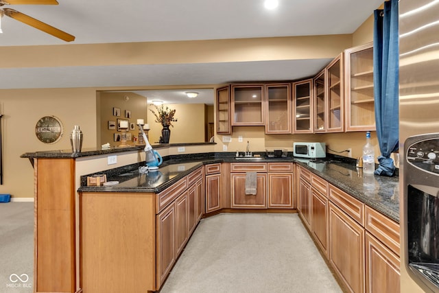 705 Ridge Gate Dr, Brownsburg, IN 46112 - kitchen featuring white microwave, light carpet, a peninsula, fridge, and dark stone countertops