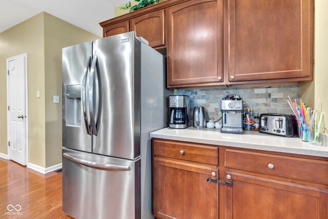 705 Ridge Gate Dr, Brownsburg, IN 46112 - kitchen with stainless steel refrigerator with ice dispenser, light wood-style flooring, decorative backsplash, light countertops, and brown cabinetry