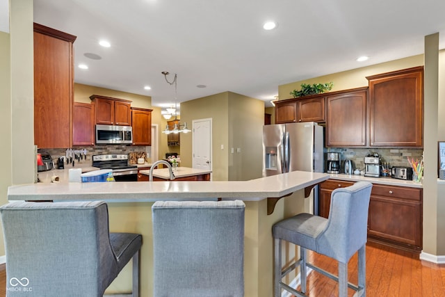 705 Ridge Gate Dr, Brownsburg, IN 46112 - kitchen featuring stainless steel appliances, a peninsula, light wood-type flooring, tasteful backsplash, and recessed lighting