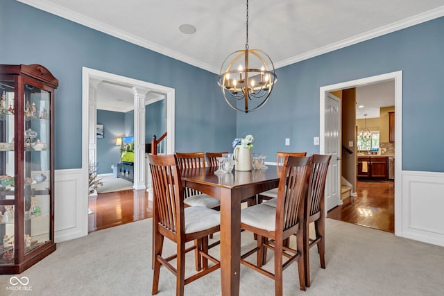 705 Ridge Gate Dr, Brownsburg, IN 46112 - dining area featuring ornamental molding, a chandelier, light colored carpet, ornate columns, and light wood-style floors