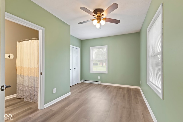 7928 Vontress St, Coatesville, IN 46121 - unfurnished bedroom featuring a baseboard radiator, wood finished floors, a closet, and a ceiling fan