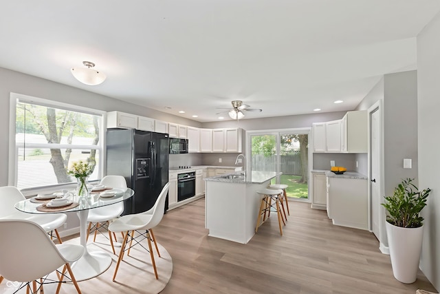 7928 Vontress St, Coatesville, IN 46121 - kitchen with black appliances, white cabinetry, a center island with sink, a breakfast bar area, and recessed lighting