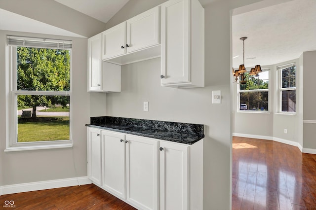 9055 Glass Chimney Ln, Fishers, IN 46037 - kitchen featuring dark wood-style floors, white cabinetry, lofted ceiling, dark stone countertops, and a chandelier