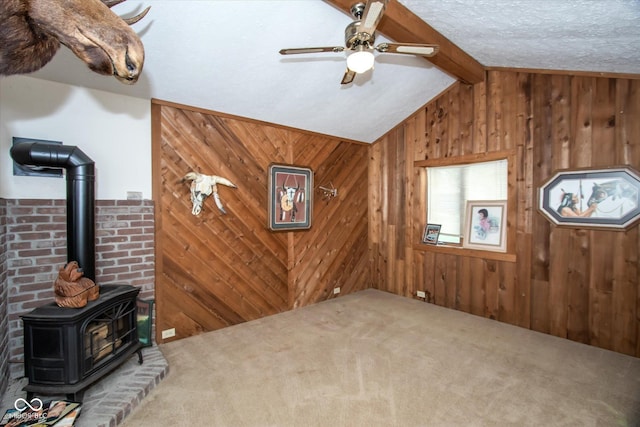 5538 N 700 W, Mccordsville, IN 46055 - unfurnished living room featuring a wood stove, wooden walls, carpet floors, a ceiling fan, and a textured ceiling
