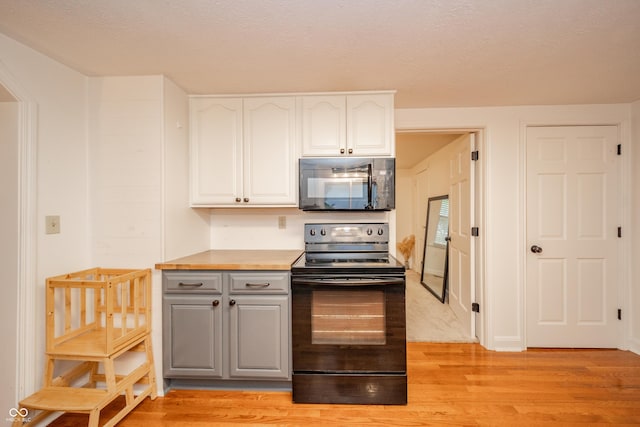 4491 W 600 N, Anderson, IN 46011 - kitchen with black appliances, gray cabinetry, light wood-style flooring, white cabinets, and light countertops