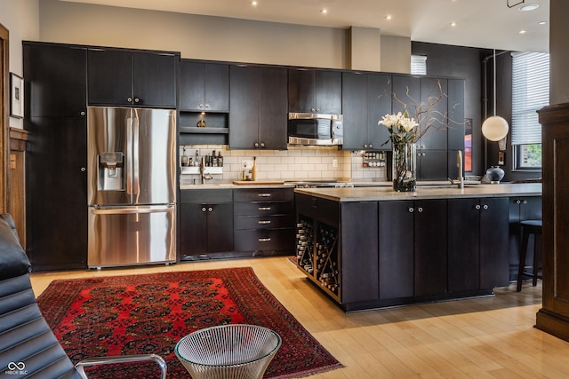 3959 Central Ave, Indianapolis, IN 46205 - kitchen featuring appliances with stainless steel finishes, decorative backsplash, light countertops, light wood-type flooring, and recessed lighting