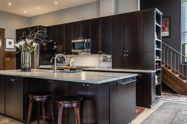 3959 Central Ave, Indianapolis, IN 46205 - kitchen with stainless steel microwave, decorative backsplash, a kitchen island with sink, a breakfast bar area, and fridge