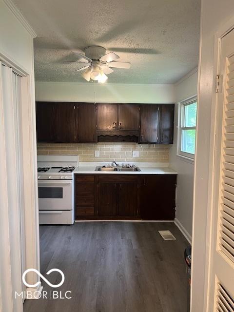 5312 N Kercheval Dr, Indianapolis, IN 46226 - kitchen with gas range gas stove, dark wood-style flooring, a textured ceiling, dark brown cabinetry, and decorative backsplash