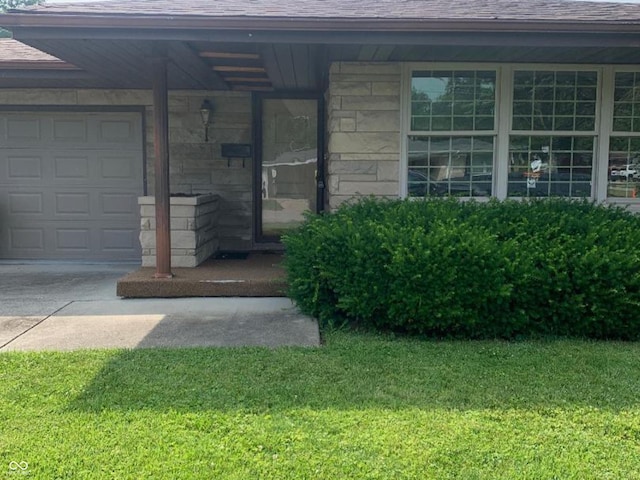 24 David Dr, North Vernon, IN 47265 - property entrance with a lawn, stone siding, roof with shingles, concrete driveway, and a garage