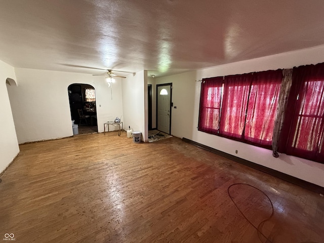 1227 W 9th St, Anderson, IN 46016 - unfurnished living room with arched walkways, ceiling fan, and wood finished floors