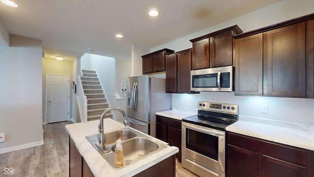 16551 Branham Dr, Fishers, IN 46040 - kitchen featuring appliances with stainless steel finishes, a kitchen island with sink, light wood-style floors, light countertops, and recessed lighting