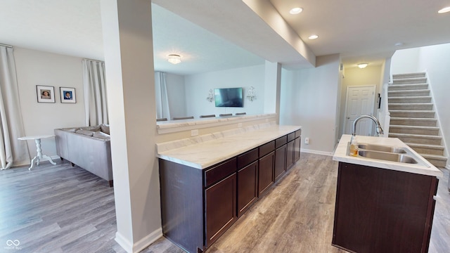 16551 Branham Dr, Fishers, IN 46040 - kitchen with light wood-type flooring, a center island with sink, dark brown cabinetry, open floor plan, and light countertops