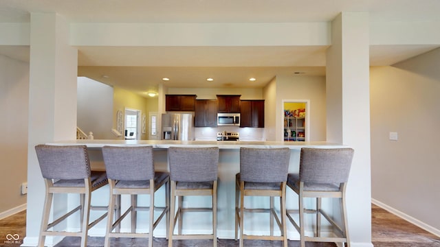 16551 Branham Dr, Fishers, IN 46040 - kitchen featuring stainless steel appliances, light countertops, a peninsula, a kitchen bar, and recessed lighting