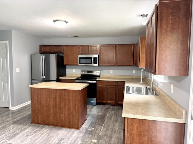 3314 Montgomery Dr, Indianapolis, IN 46227 - kitchen with appliances with stainless steel finishes, light countertops, dark wood-type flooring, a kitchen island, and brown cabinetry