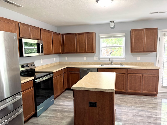 3314 Montgomery Dr, Indianapolis, IN 46227 - kitchen with appliances with stainless steel finishes, light countertops, light wood-style flooring, a kitchen island, and a textured ceiling