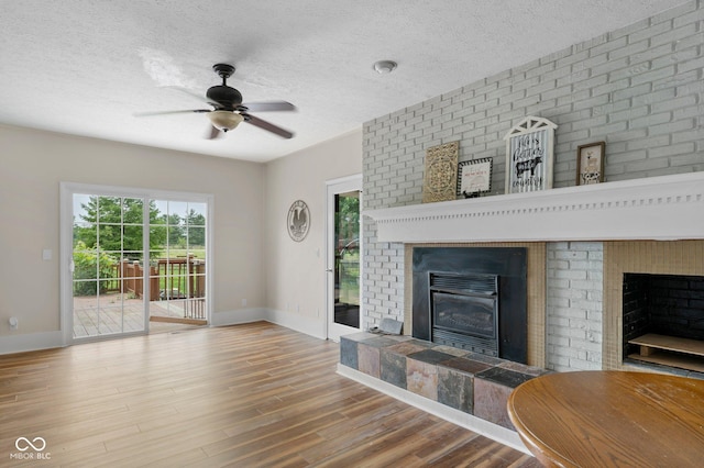 925 W Hancock Rd, Scottsburg, IN 47170 - living room with a fireplace, ceiling fan, wood finished floors, plenty of natural light, and a textured ceiling