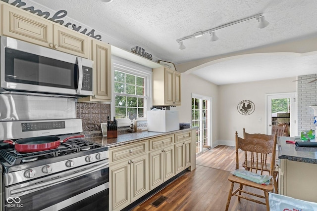 925 W Hancock Rd, Scottsburg, IN 47170 - kitchen with cream cabinetry, stainless steel appliances, arched walkways, tasteful backsplash, and dark wood finished floors