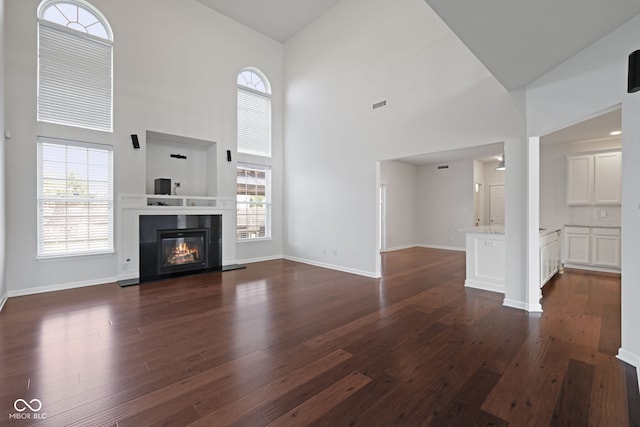 2078 Seneca Ln, Plainfield, IN 46168 - unfurnished living room with a towering ceiling, dark wood finished floors, and a glass covered fireplace