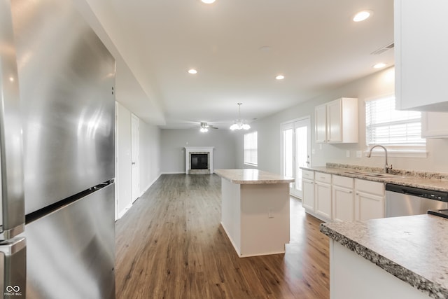 413 Youngs Creek Ct, Franklin, IN 46131 - kitchen with appliances with stainless steel finishes, a glass covered fireplace, wood finished floors, recessed lighting, and white cabinets