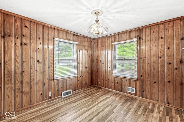 4010 S Bazil Ave, Indianapolis, IN 46239 - unfurnished room featuring a chandelier, plenty of natural light, hardwood / wood-style floors, and wood walls