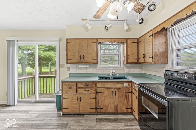 4010 S Bazil Ave, Indianapolis, IN 46239 - kitchen featuring electric range, brown cabinets, plenty of natural light, light wood-style floors, and a textured ceiling