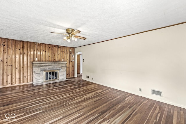 4010 S Bazil Ave, Indianapolis, IN 46239 - unfurnished living room featuring arched walkways, dark wood finished floors, a ceiling fan, a textured ceiling, and wood walls