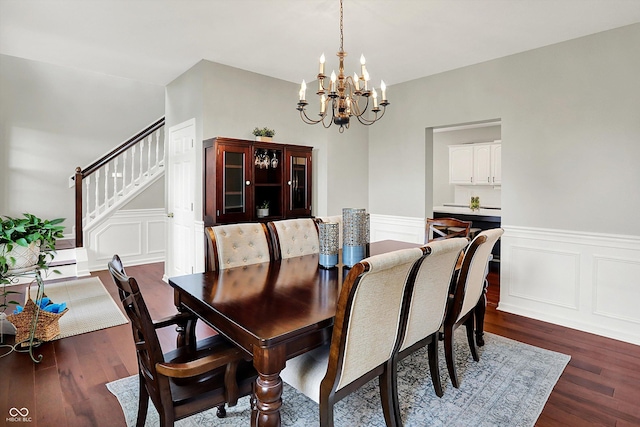 13191 Roma, Carmel, IN 46074 - dining area with a chandelier, a decorative wall, dark wood finished floors, a wainscoted wall, and stairs