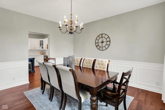 13191 Roma, Carmel, IN 46074 - dining space with a chandelier, dark wood finished floors, a wainscoted wall, and a decorative wall