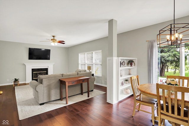 13191 Roma, Carmel, IN 46074 - living room featuring a chandelier, dark wood-style flooring, ceiling fan, and a glass covered fireplace