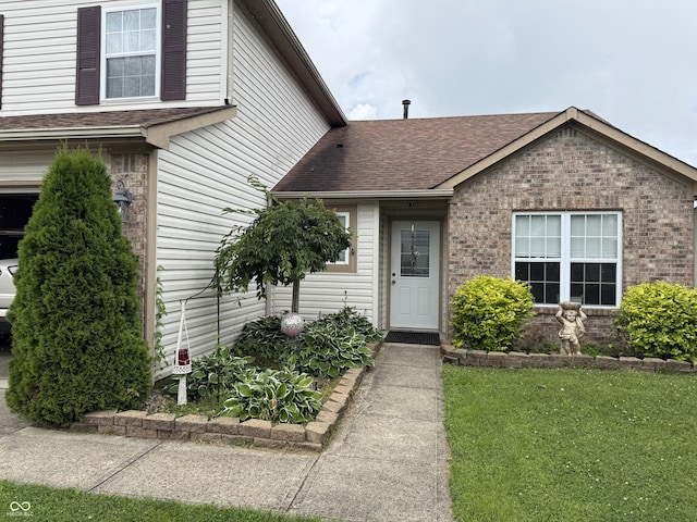 982 Ramsgate Rd, Greenwood, IN 46143 - doorway to property with brick siding, roof with shingles, and a yard