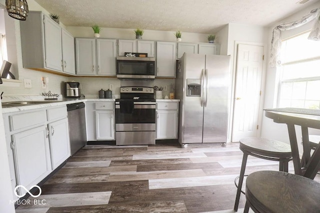 982 Ramsgate Rd, Greenwood, IN 46143 - kitchen with appliances with stainless steel finishes, a textured ceiling, light countertops, light wood-style floors, and decorative backsplash