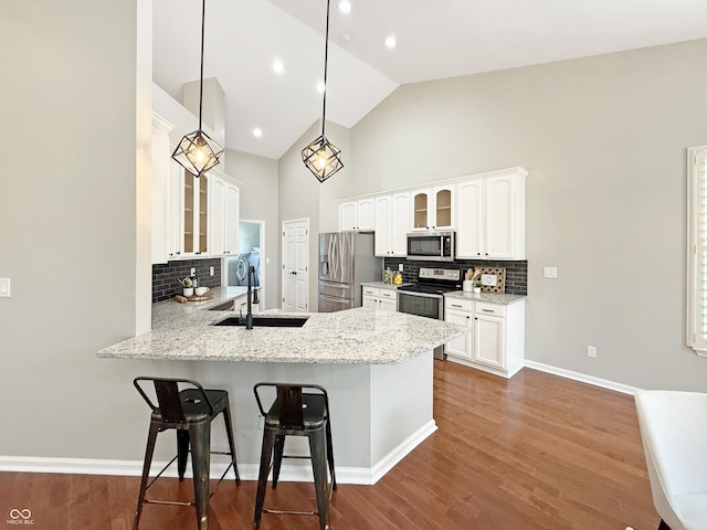 9302 N Bayland Dr, Mccordsville, IN 46055 - kitchen featuring stainless steel appliances, glass insert cabinets, a kitchen bar, a peninsula, and decorative backsplash